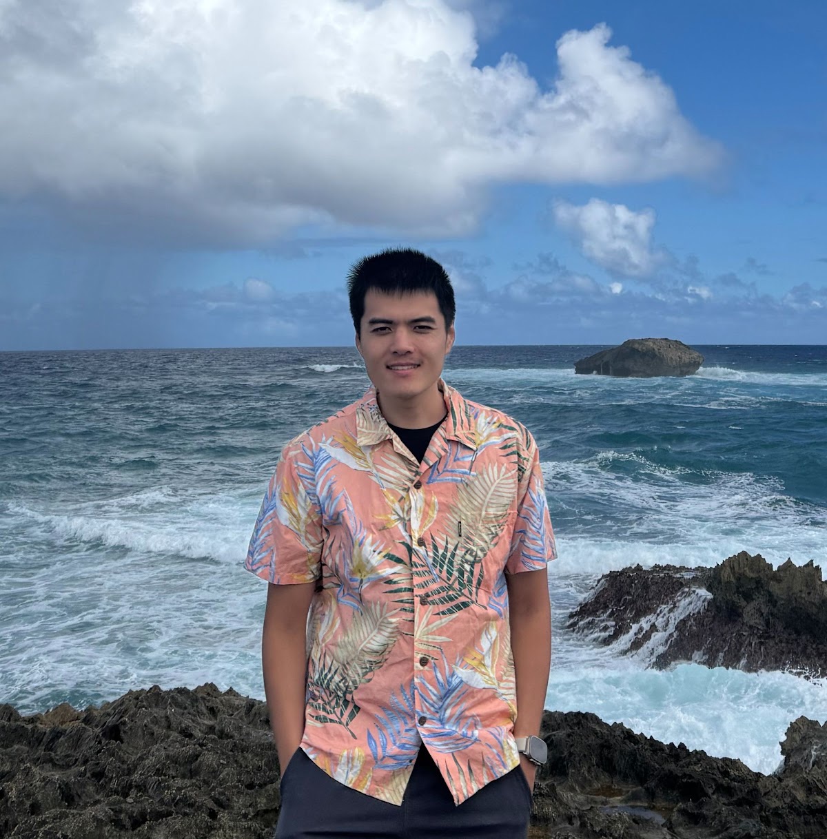 Yaguang Li standing on a rocky shoreline in Hawaiʻi